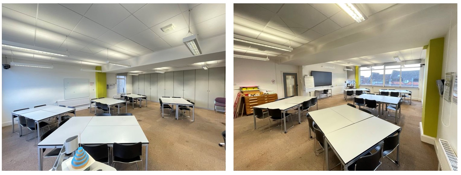 Chairs and tables in small groups around the room. The room has whiteboards fixed to the walls. The floor is carpeted.